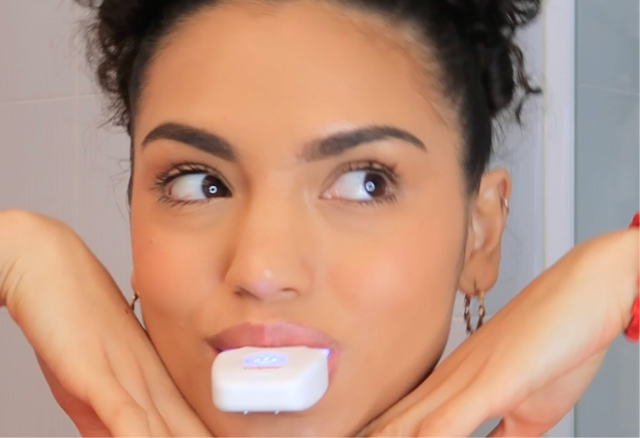 女士咬合牙托並啟動牙齒美白燈。